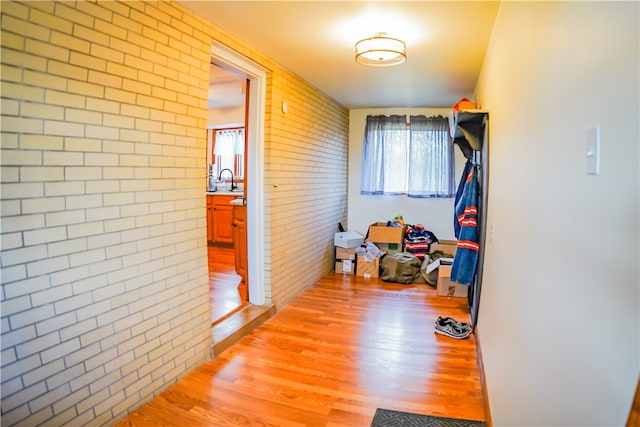 hall featuring light hardwood / wood-style floors, a wealth of natural light, and brick wall