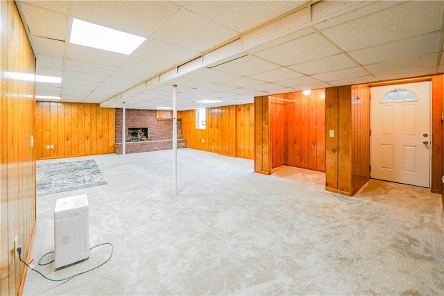 basement featuring carpet flooring, a paneled ceiling, and wood walls