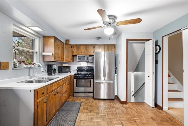 kitchen with ceiling fan, sink, light parquet flooring, and appliances with stainless steel finishes