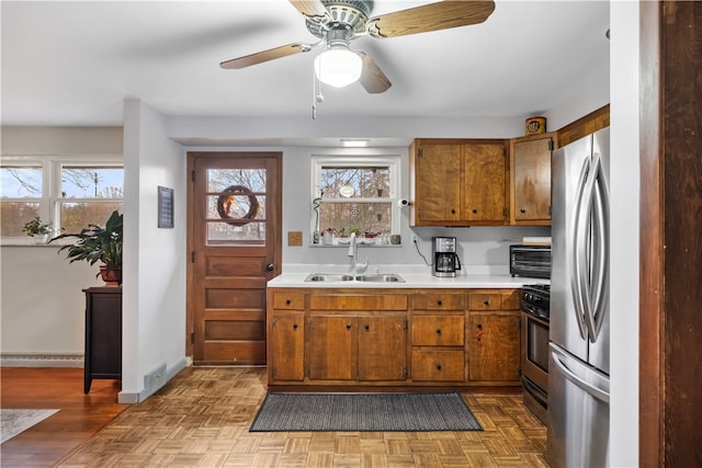 kitchen with a wealth of natural light, sink, light parquet floors, and stainless steel appliances