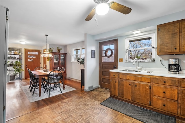 kitchen featuring decorative light fixtures, ceiling fan, and sink