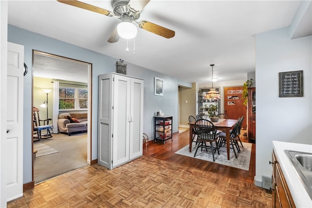 dining room with ceiling fan, sink, and light colored carpet