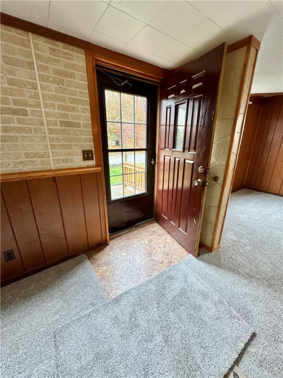 entryway with wood walls and light colored carpet