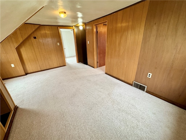 carpeted empty room featuring wood walls and lofted ceiling