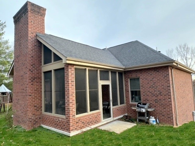 back of property featuring a lawn and a sunroom