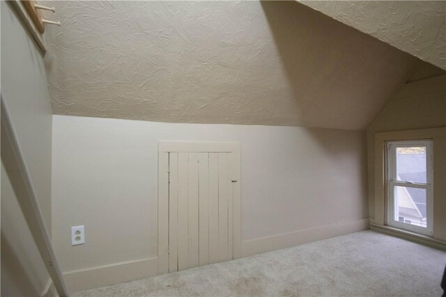 bonus room with carpet flooring, a textured ceiling, and vaulted ceiling