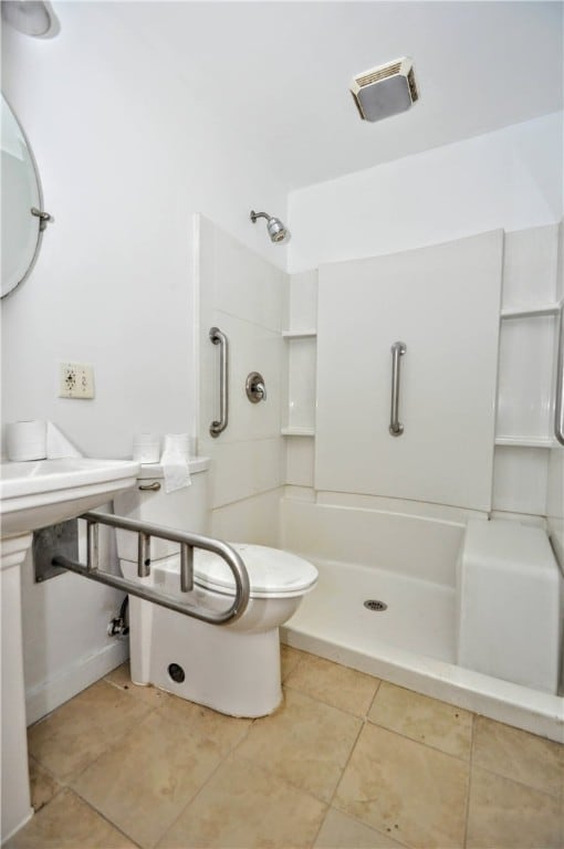 bathroom with a shower, tile patterned flooring, and toilet