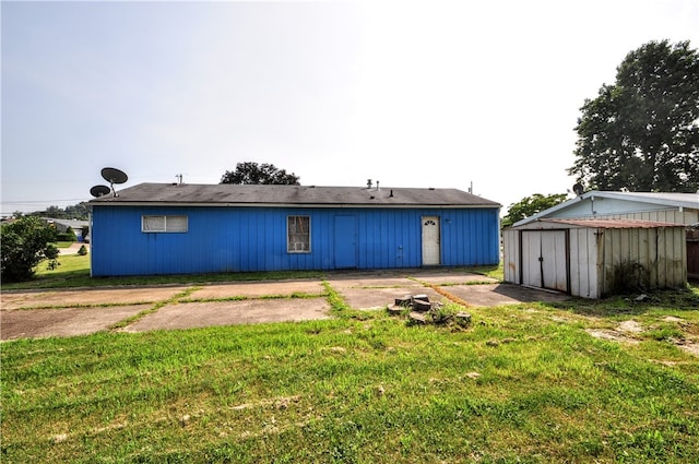 rear view of property featuring a storage shed and a lawn