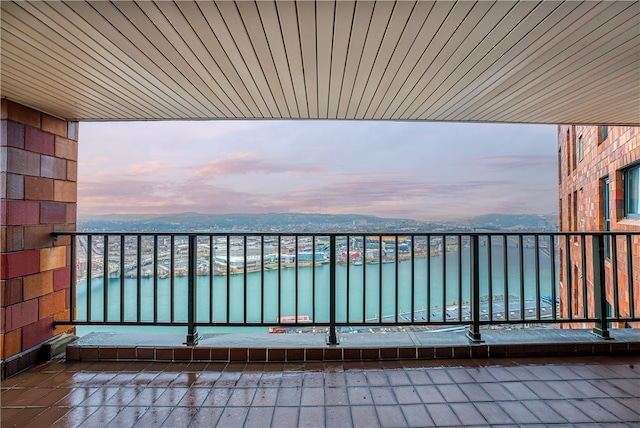 balcony at dusk featuring a water view