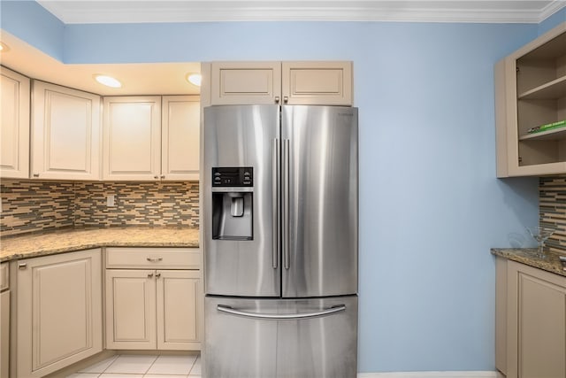 kitchen featuring decorative backsplash, stainless steel fridge, light stone counters, crown molding, and light tile patterned flooring