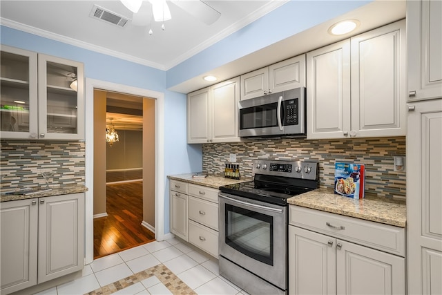 kitchen featuring appliances with stainless steel finishes, white cabinetry, light tile patterned floors, and ornamental molding