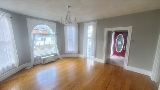 unfurnished dining area with radiator heating unit, an inviting chandelier, and light wood-type flooring