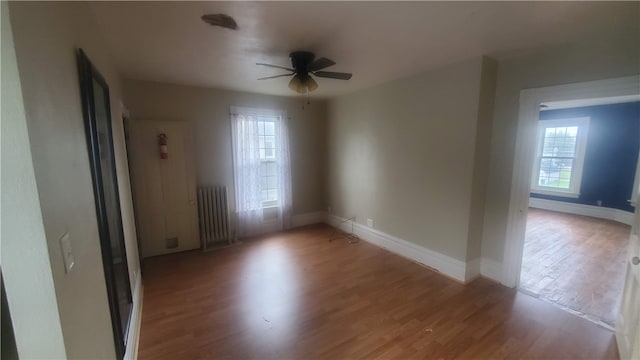 unfurnished room featuring radiator heating unit, a healthy amount of sunlight, and light hardwood / wood-style floors