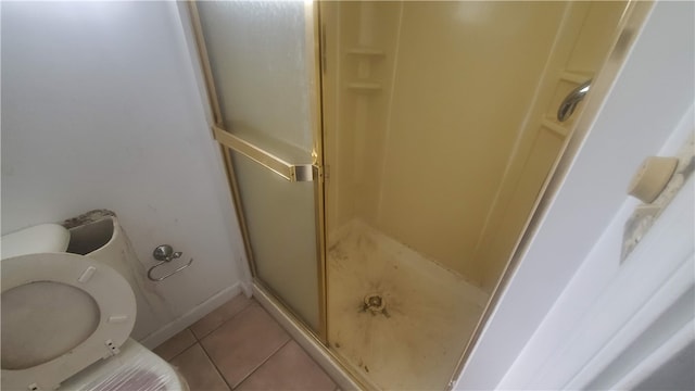 bathroom featuring toilet, tile patterned floors, and a shower with shower door