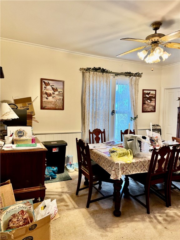 carpeted dining space featuring ceiling fan, crown molding, and wooden walls