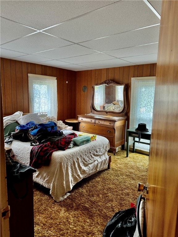 carpeted bedroom with wooden walls and a drop ceiling