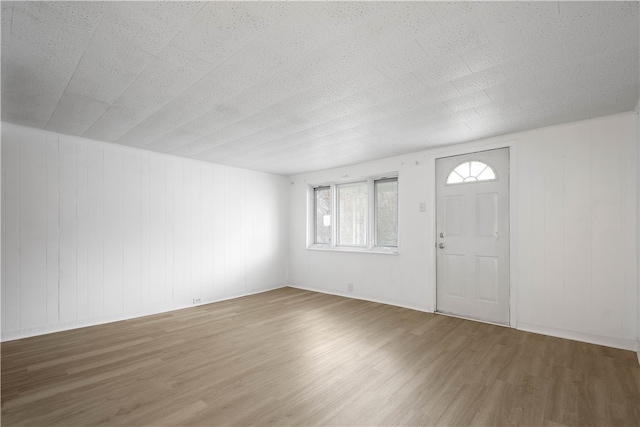 entrance foyer with hardwood / wood-style floors and wooden walls