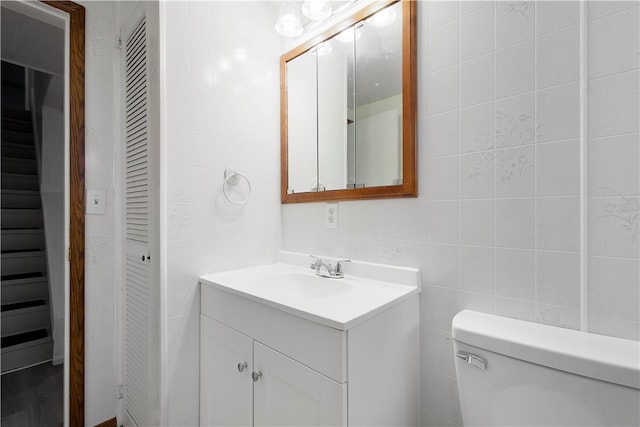 bathroom with vanity, tile walls, and toilet