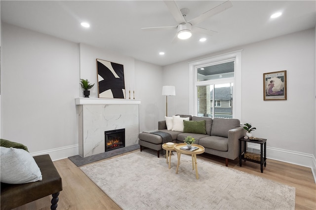 living room with ceiling fan, light hardwood / wood-style floors, and a fireplace