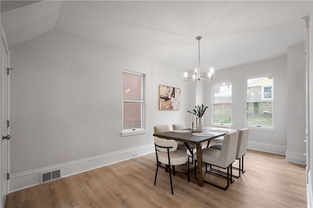 dining area featuring light hardwood / wood-style floors, vaulted ceiling, and a notable chandelier