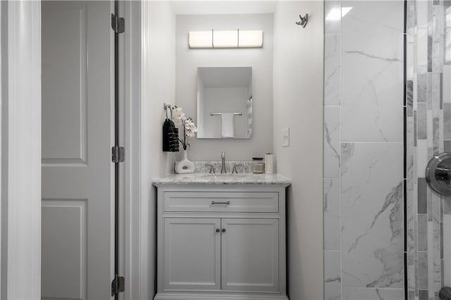 bathroom with a tile shower and vanity