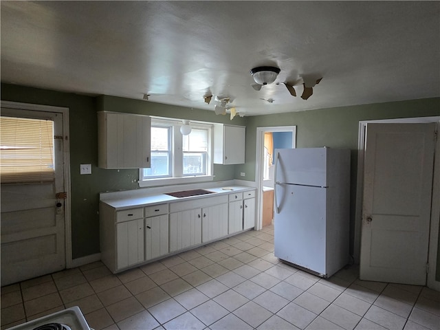 kitchen with white fridge, white cabinetry, and light tile patterned flooring