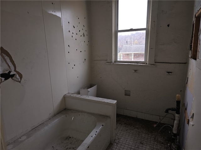 bathroom with tile patterned floors and a tub to relax in