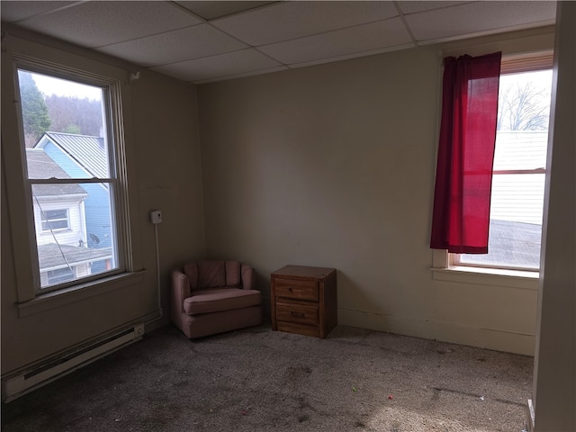 interior space with carpet flooring, a paneled ceiling, and a baseboard heating unit