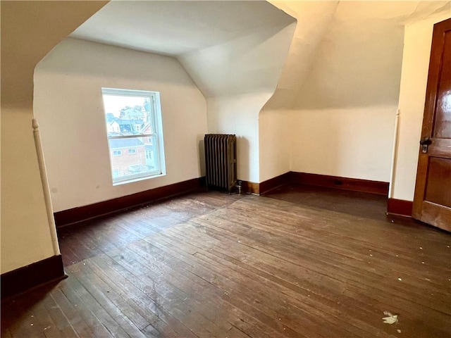 bonus room with radiator heating unit, dark hardwood / wood-style flooring, and vaulted ceiling