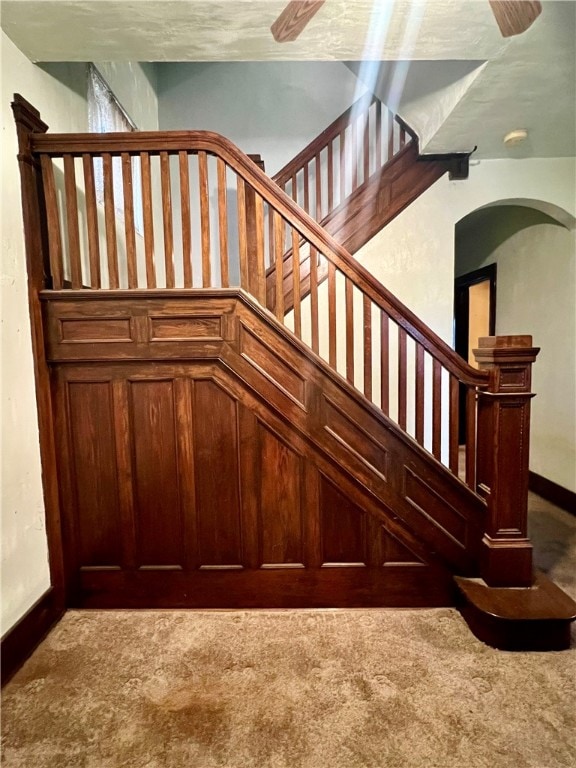 stairway with carpet floors and a textured ceiling