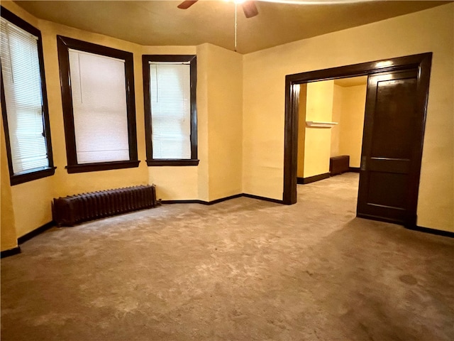 carpeted spare room with radiator and ceiling fan