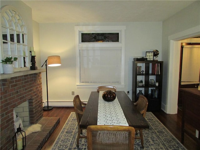 dining space featuring baseboard heating, a fireplace, and dark hardwood / wood-style floors