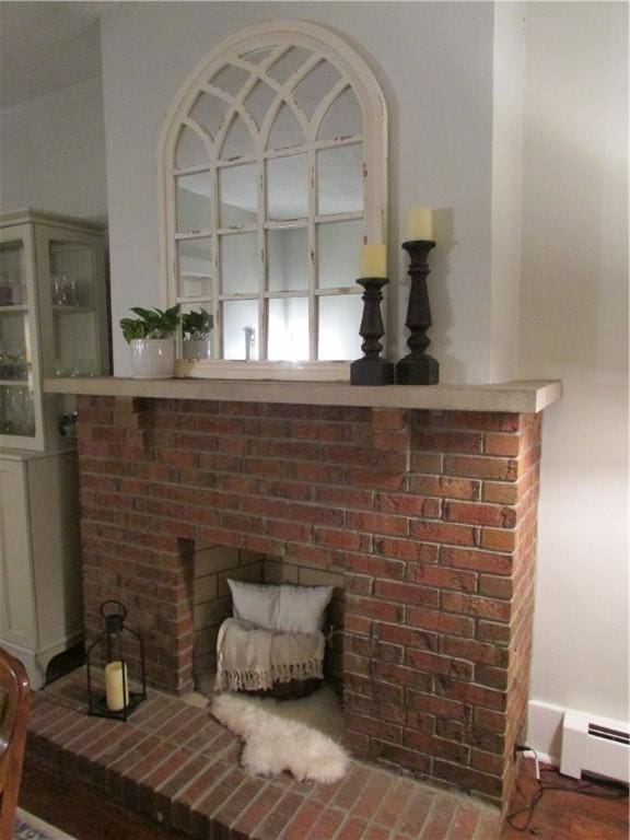 room details featuring a baseboard radiator and a brick fireplace