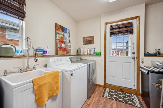 laundry area with separate washer and dryer, a wealth of natural light, and light hardwood / wood-style floors