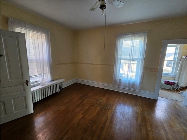 spare room featuring ceiling fan, radiator heating unit, and dark wood-type flooring