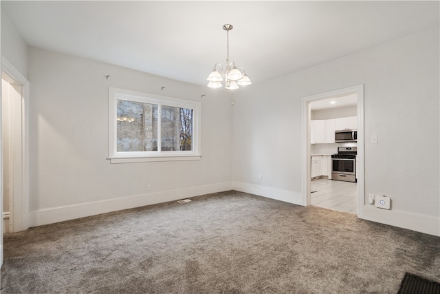 empty room with light carpet and a notable chandelier