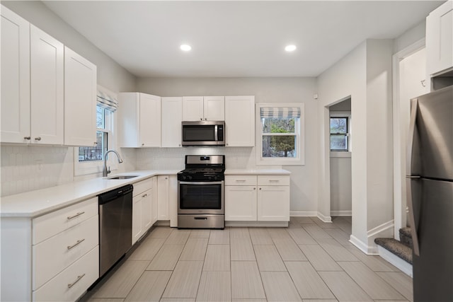 kitchen with appliances with stainless steel finishes, tasteful backsplash, white cabinetry, and sink