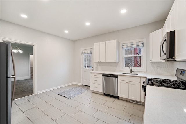 kitchen with backsplash, sink, white cabinetry, stainless steel appliances, and a chandelier