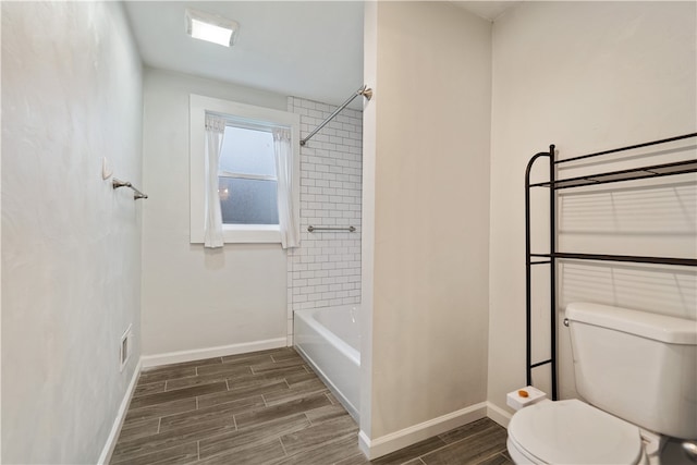 bathroom featuring hardwood / wood-style flooring, tiled shower / bath, and toilet