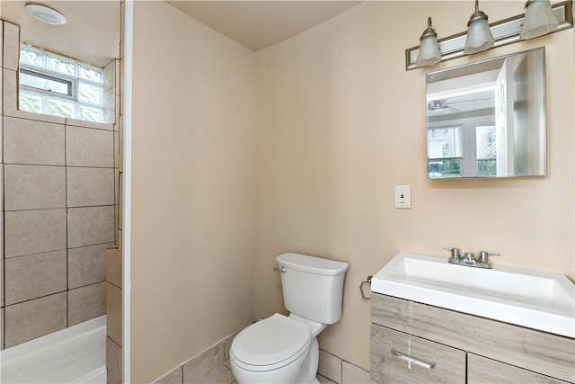 bathroom featuring tiled shower, tile patterned flooring, vanity, and toilet