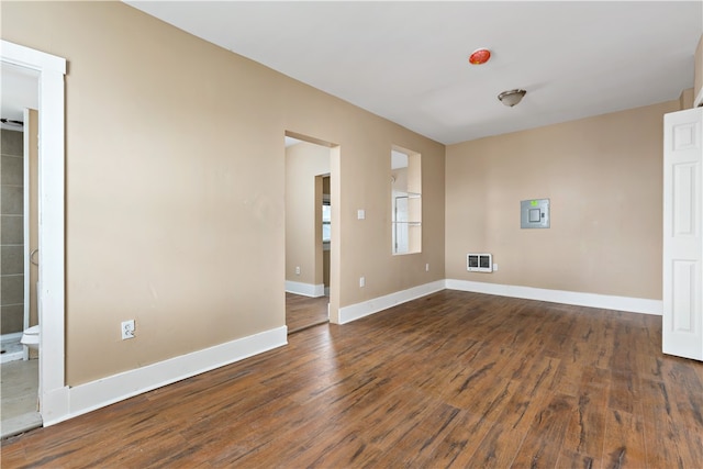 spare room featuring heating unit and dark hardwood / wood-style flooring