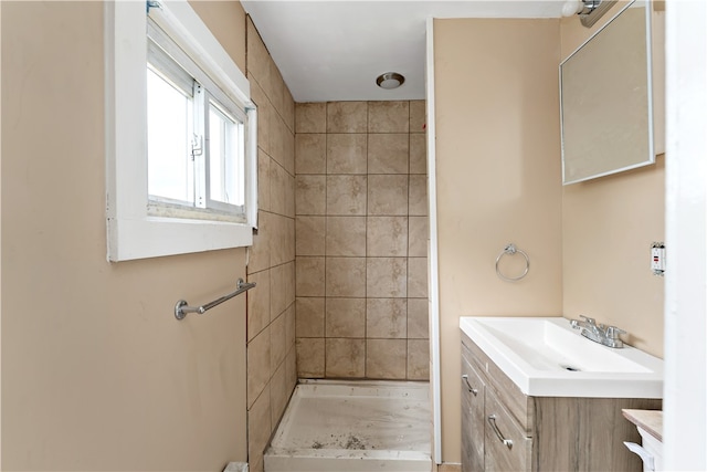 bathroom with a tile shower and vanity