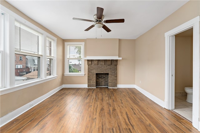 unfurnished living room with ceiling fan, a fireplace, and wood-type flooring