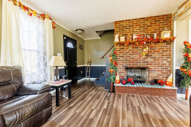 living room with hardwood / wood-style floors, a textured ceiling, and a brick fireplace