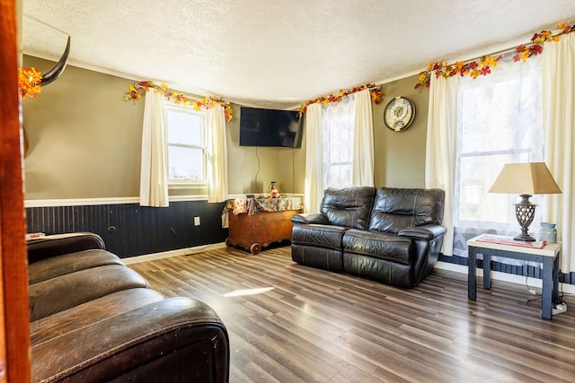 living room with wood walls, ornamental molding, a textured ceiling, and hardwood / wood-style flooring