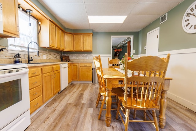 kitchen with sink, hanging light fixtures, backsplash, white appliances, and a paneled ceiling