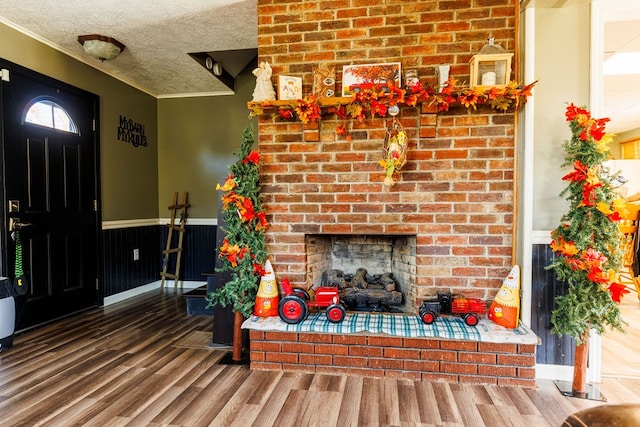 living room featuring a fireplace, ornamental molding, a textured ceiling, and hardwood / wood-style flooring