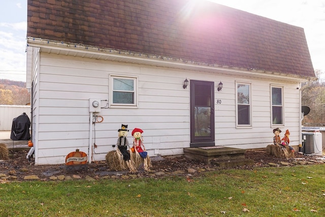 back of house with a lawn and central AC