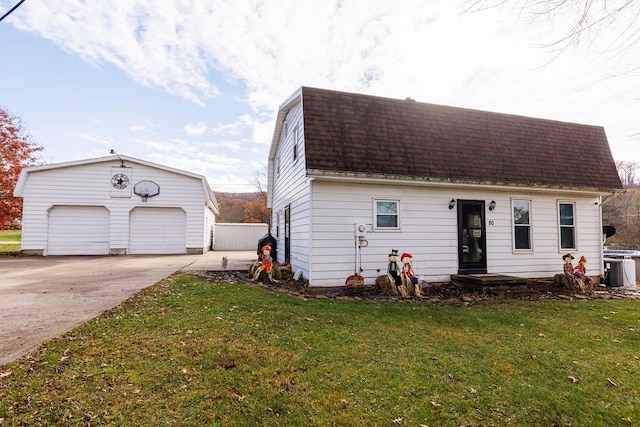 view of front facade featuring a garage, an outbuilding, a front yard, and cooling unit