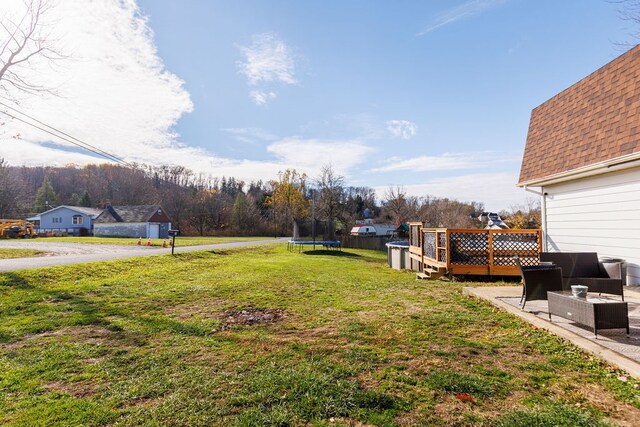 view of yard with a trampoline and a wooden deck